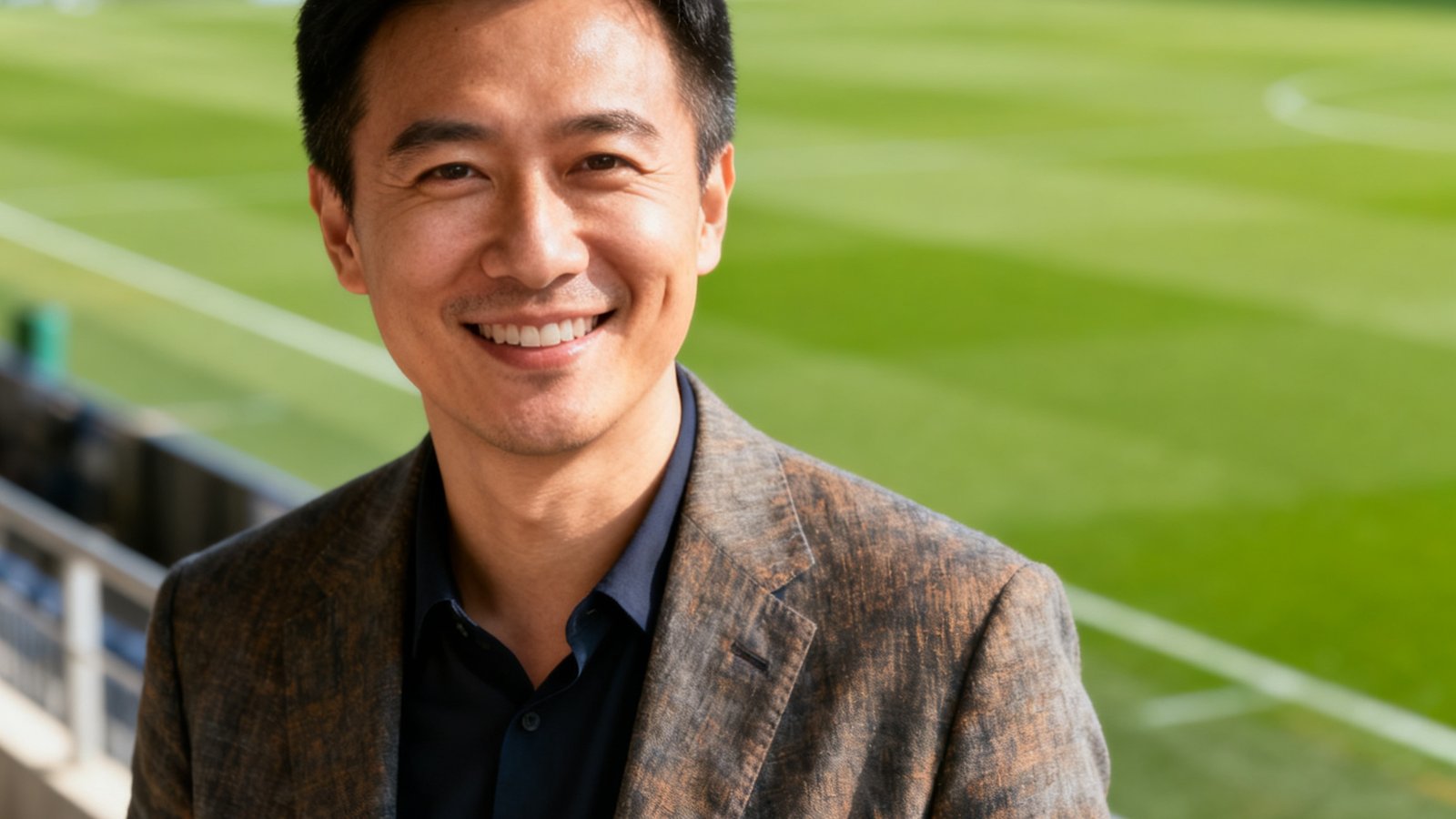 爱游戏联合创始人兼CEO，三十多岁，穿着休闲西装，在球场边微笑